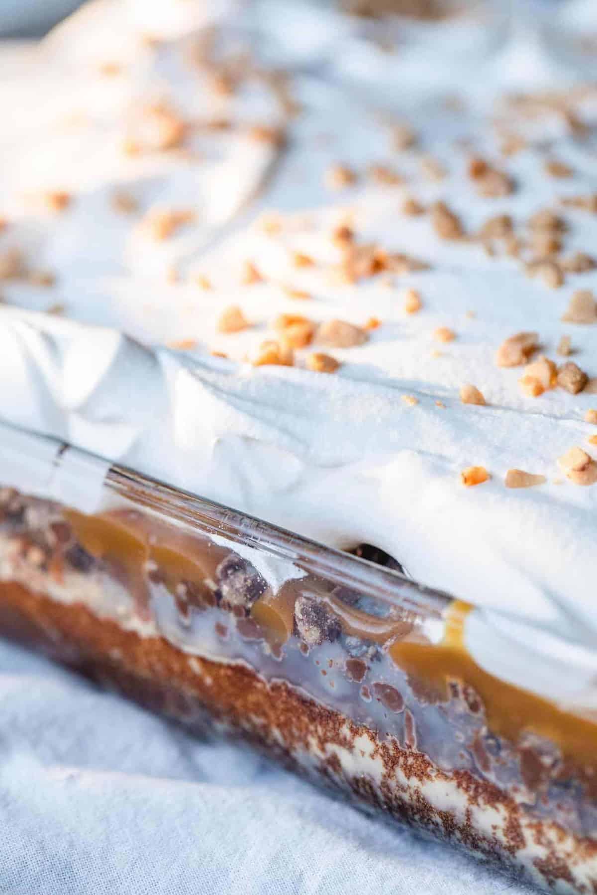 A glass baking dish holds a layered chocolate poke cake.