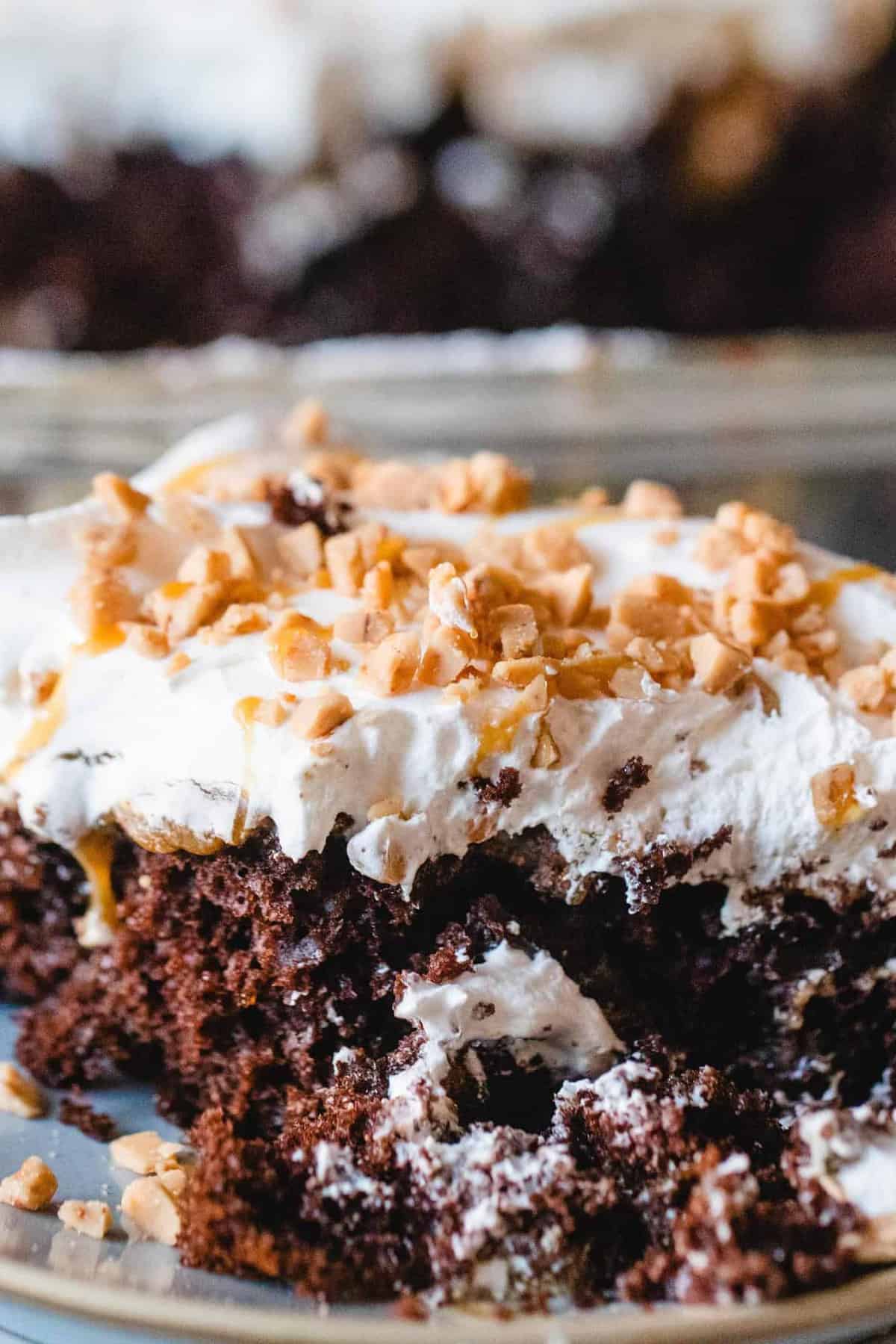 A slice of heath caramel cake sits on a plate and is being enjoyed with a fork.