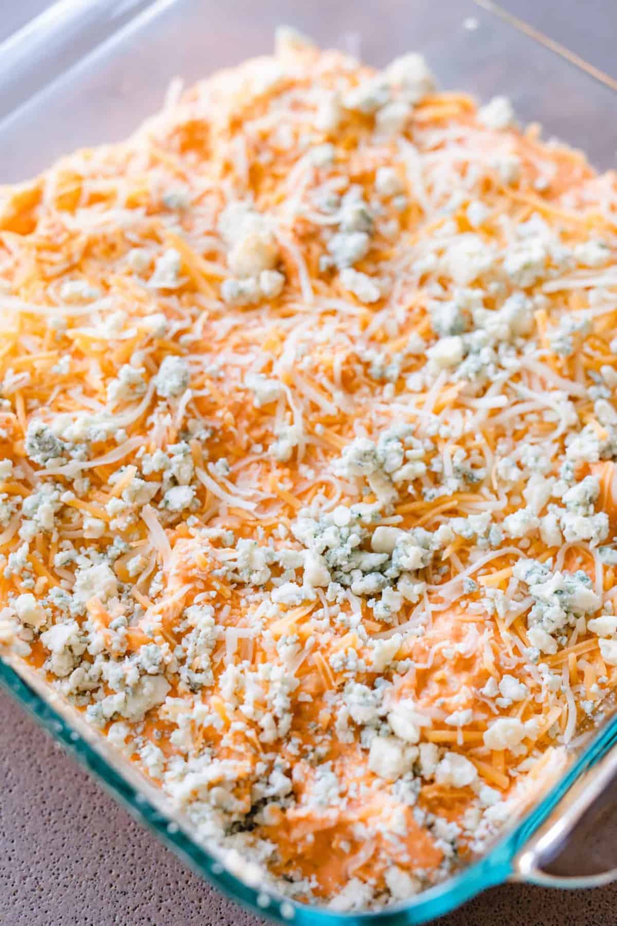 Dip mixture has been moved to a baking dish and is topped with bleu cheese crumbles.