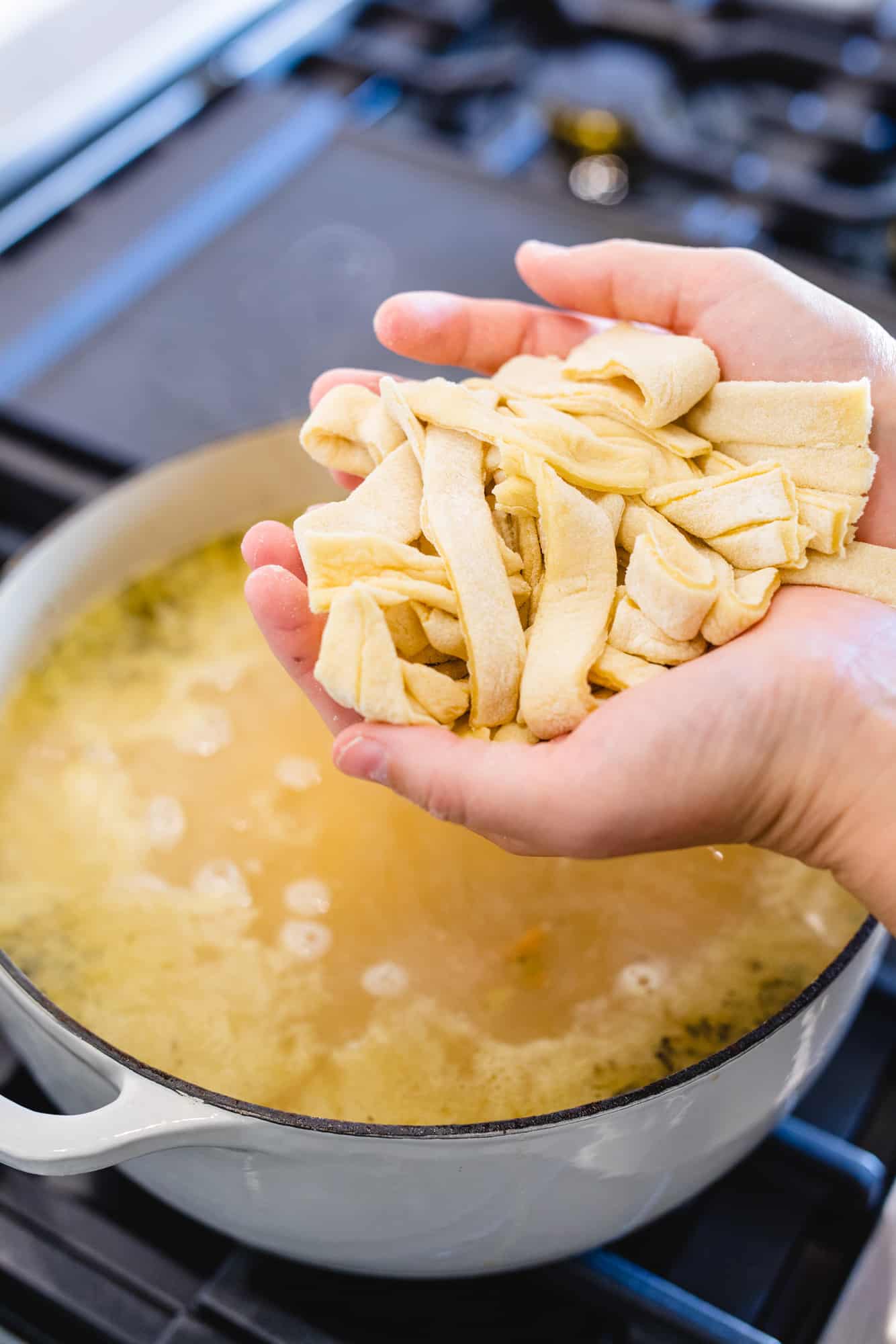 Ashley holds a large handful of homemade, fresh cut pasta.