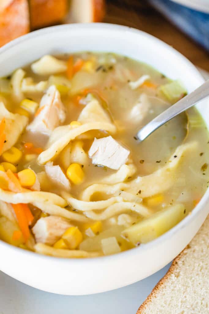 Bowl of chicken noodle soup sits with a spoon.