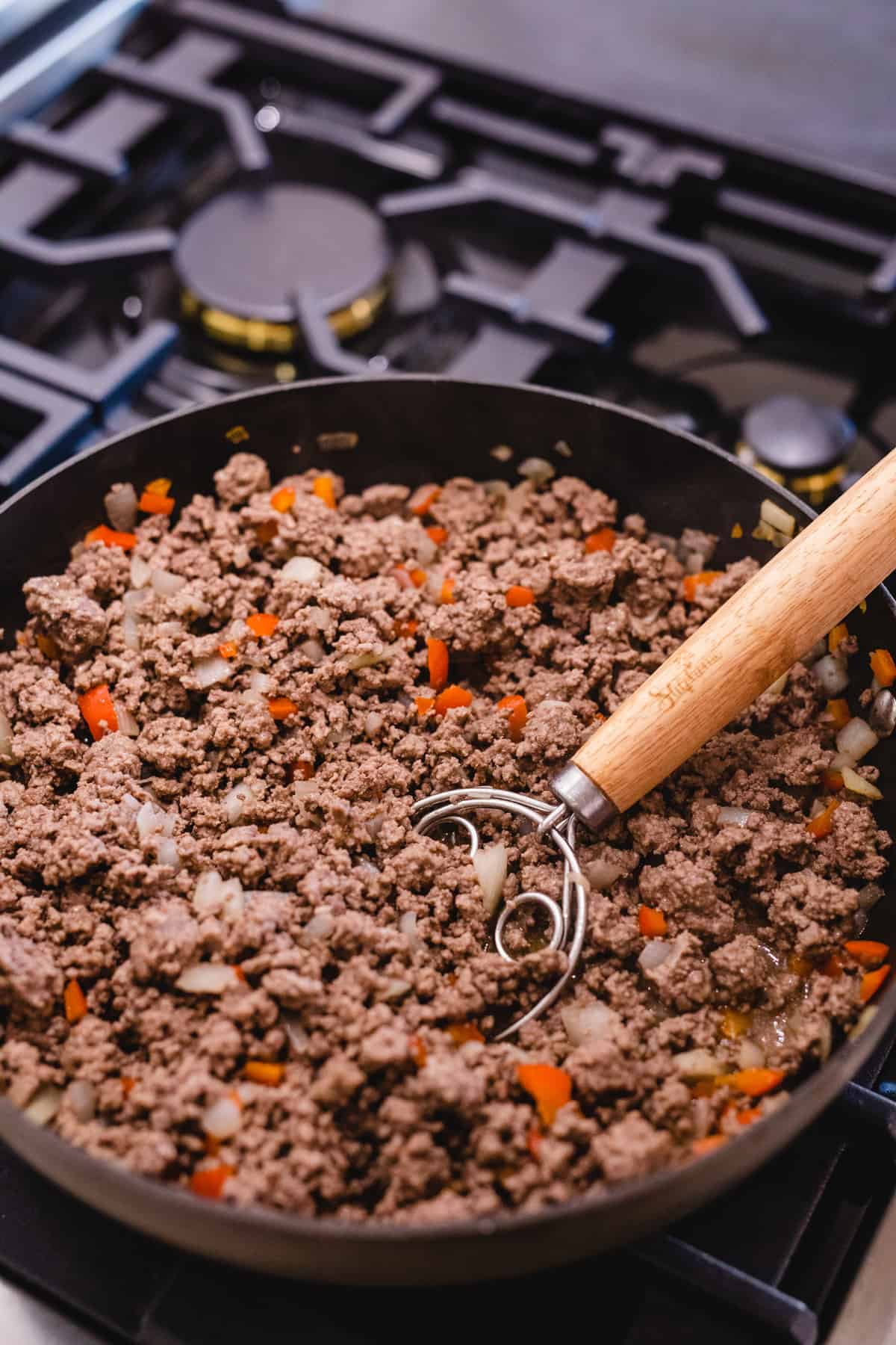 Cooked ground beef sits in a pan on a stove top.