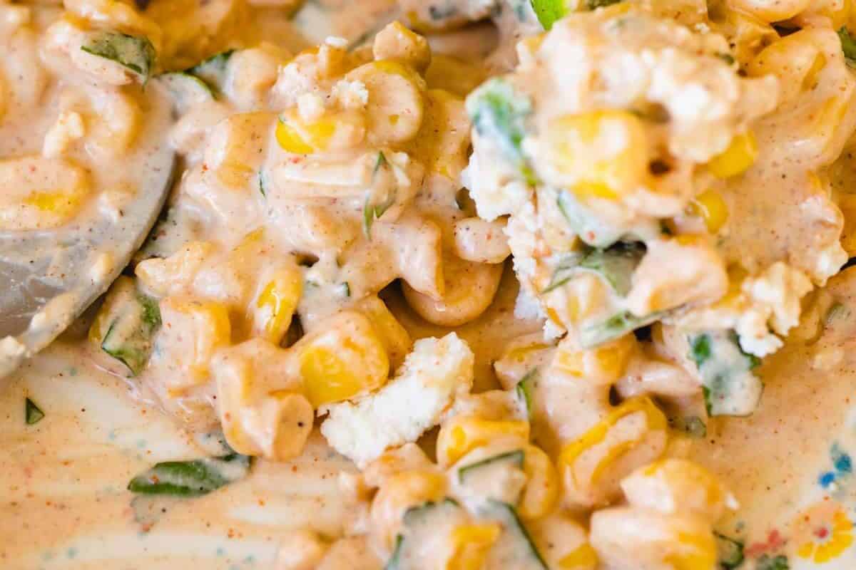 Creamy mexican corn elote sits in a casserole dish ready to serve.