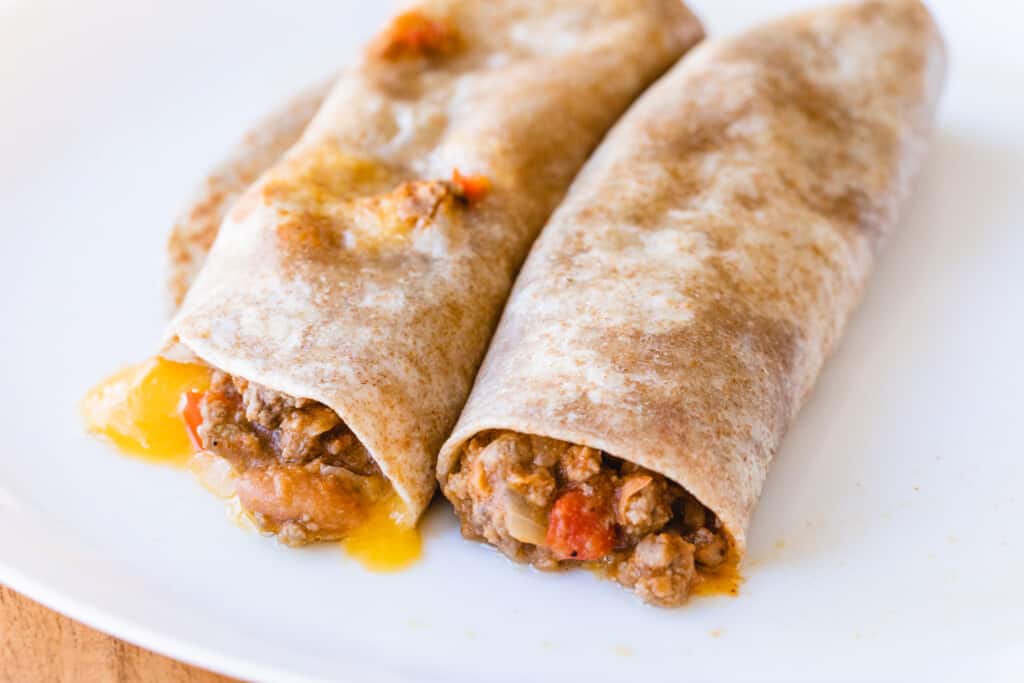 Two beef freezer burritos sit on a plate ready to enjoy.