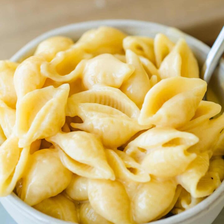 Bowl of cheesy pasta shells sits ready to eat with a fork.
