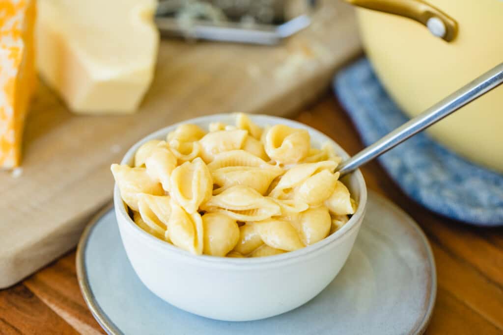 Bowl of cheesy stovetop mac and cheese sits on the counter with a fork ready to enjoy.
