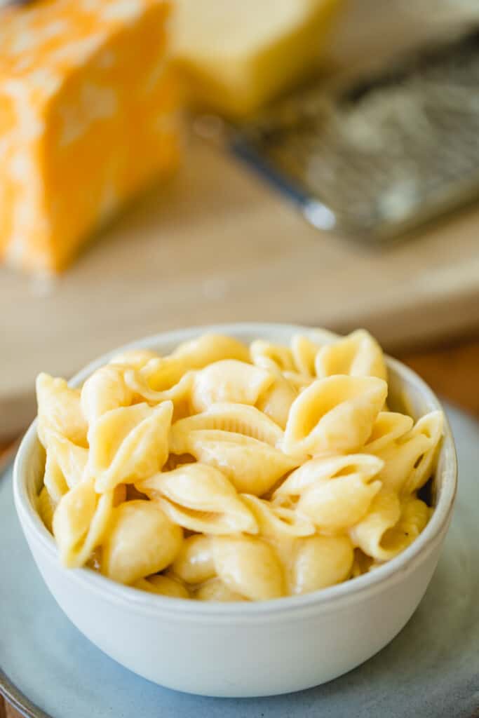 A large white bowl is filled with creamy pasta shells for Stovetop Mac and Cheese.