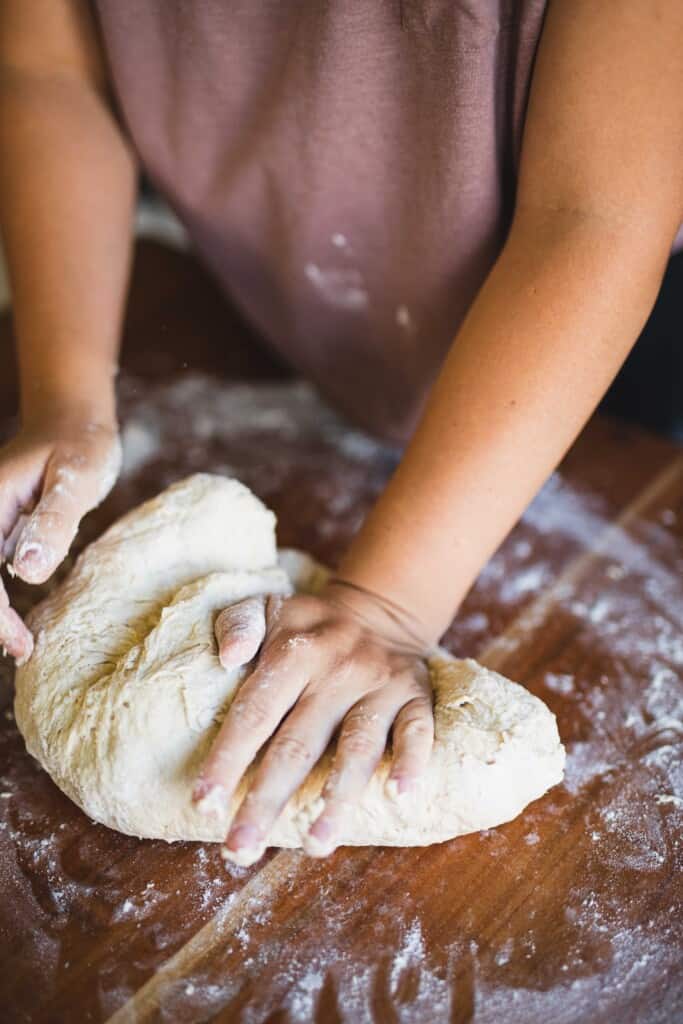 Ashley continues to knead a ball of dough with her hands.