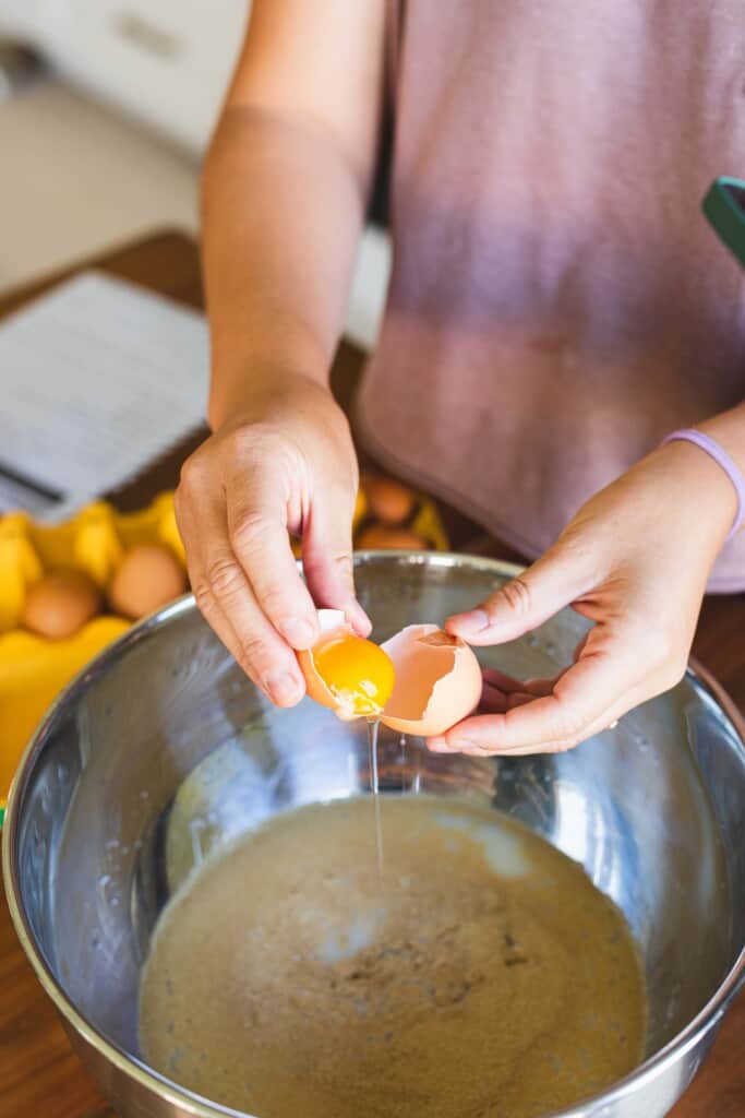 Ashley uses the empty half of a cracked egg shell to separate an egg yolk from the egg whites of a cracked egg.