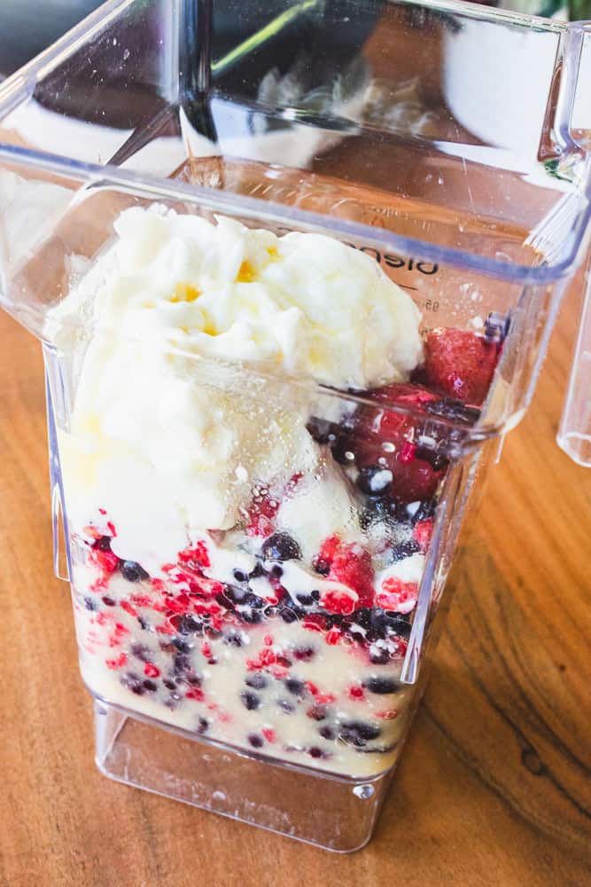 Blender cup is filled with frozen berries, pineapple juice and vanilla yogurt.