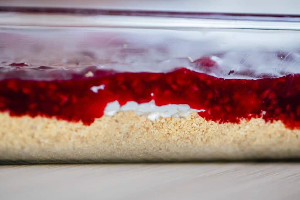 Layers for no bake raspberry cheesecake bars sits in a baking dish for serving.