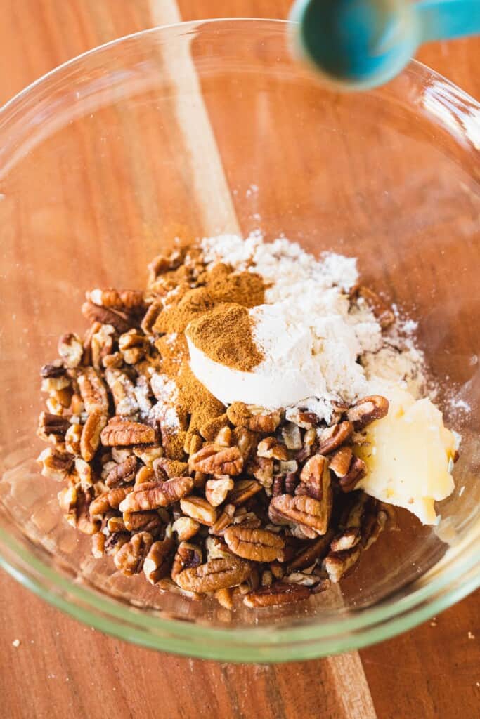 Pecans sit in a bowl with flour, brown sugar and cinnamon.