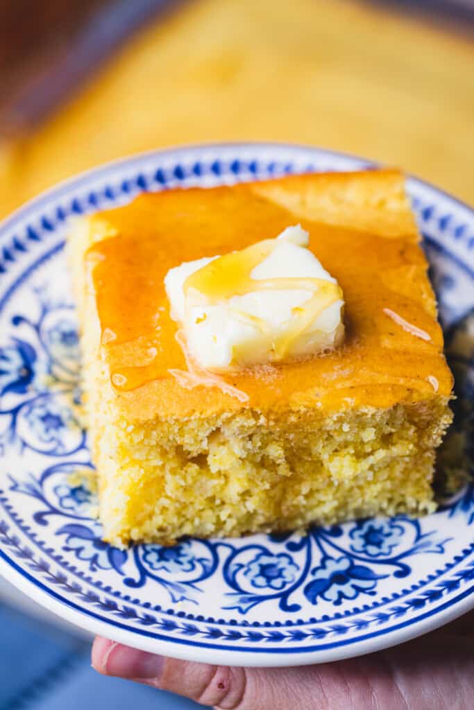 Sweet cornbread is topped with honey and a slab of butter.