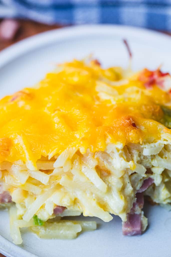 A serving of cheesy hash brown breakfast casserole sits on a small plate ready for eating.