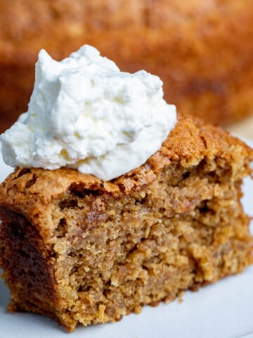 Tender and soft oatmeal cake sits topped with whipped cream.