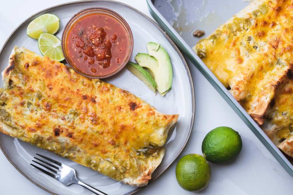 Beef enchiladas verde are served on from the dish on a large plate.