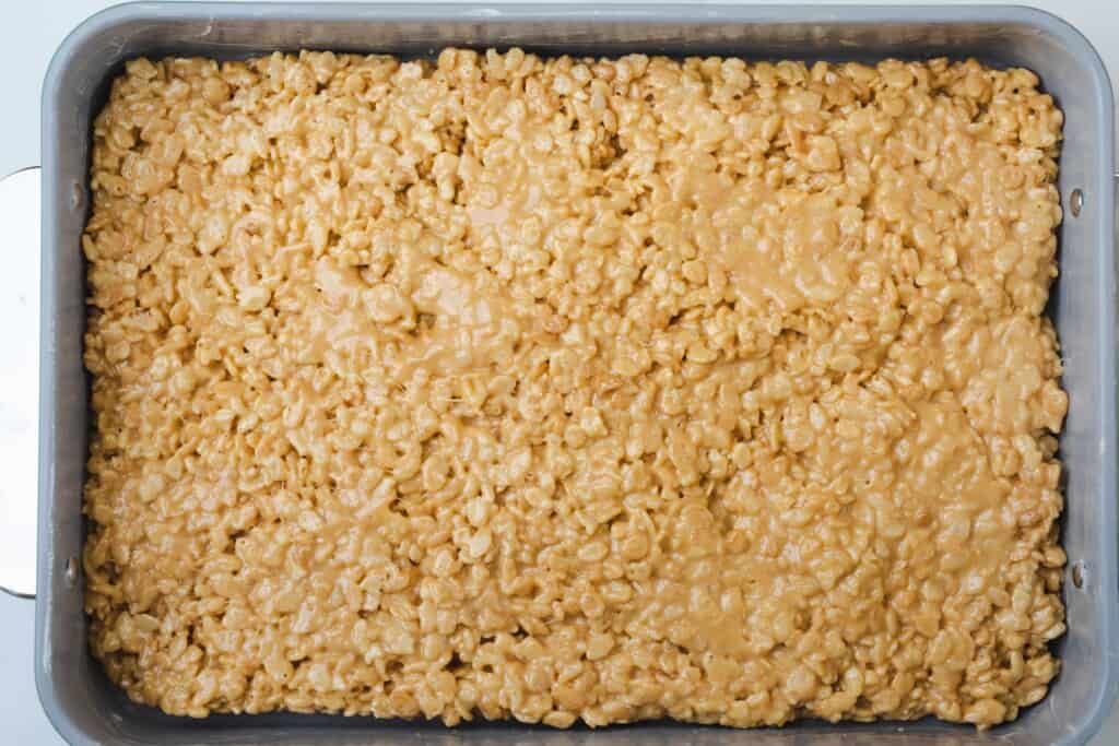 Caramel Rice Krispie treats sit in a large dish ready to be sliced into bars.
