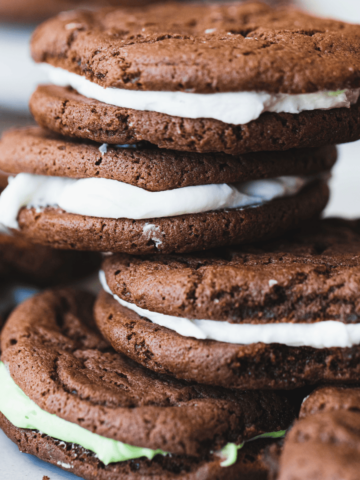 Stacks of homemade oreo or whoopie pies sit on a plate.
