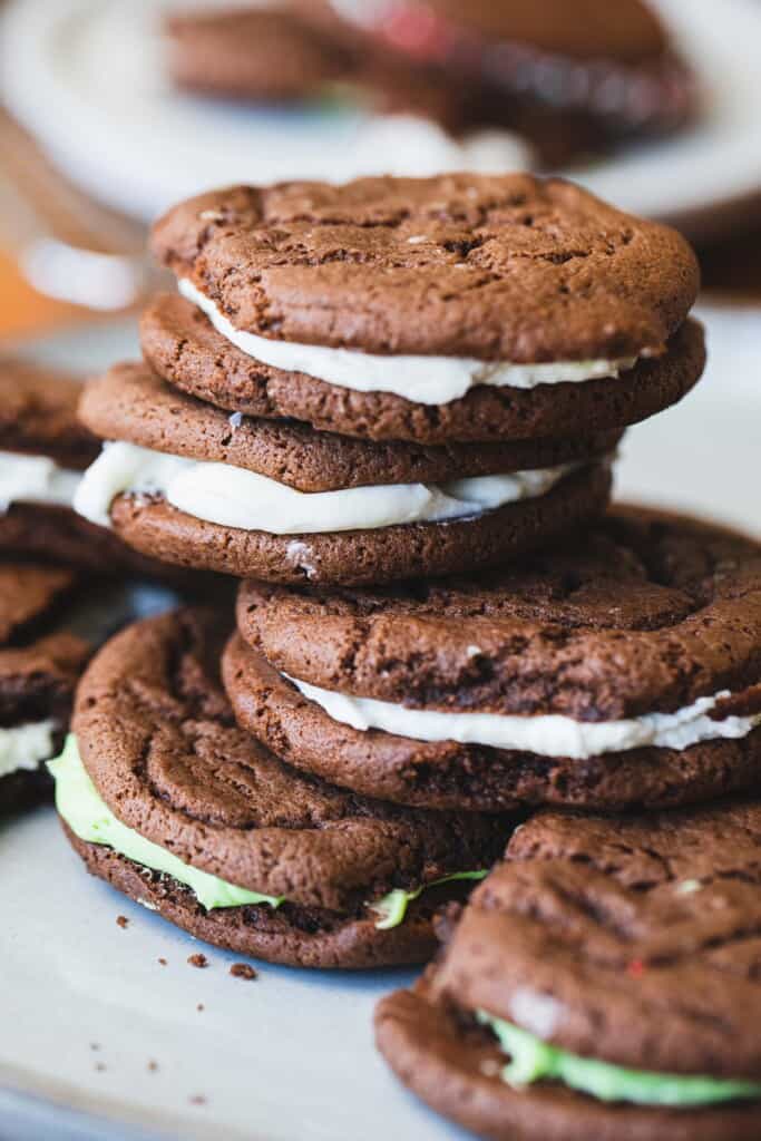 Stacks of homemade oreo or whoopie pies sit on a plate.