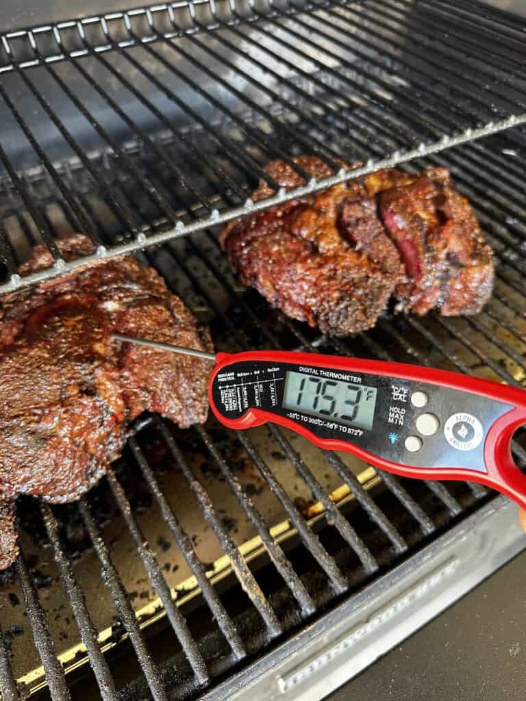 Chuck Roast is on a grill with a meat thermometer inside reading at 175.3 degrees.