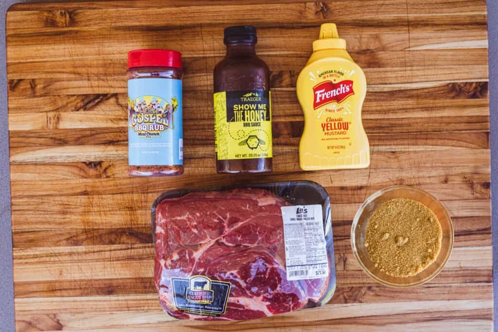 Ingredients lay on a wooden butcher block for bbq burnt ends.