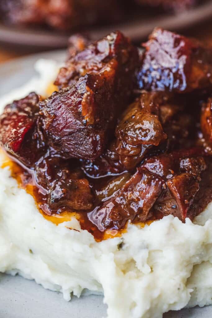 Poor man's burnt ends sit on top of a bed of fluffy mashed potatoes.