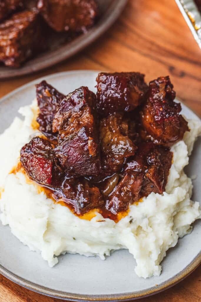 Sauced and glazed burnt ends are served with mashed potatoes for a comforting meal.