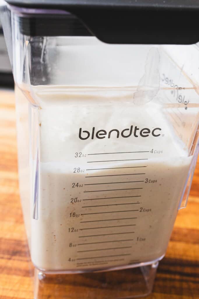 A blender cup is filled with blended white cheese dip ready to serve.