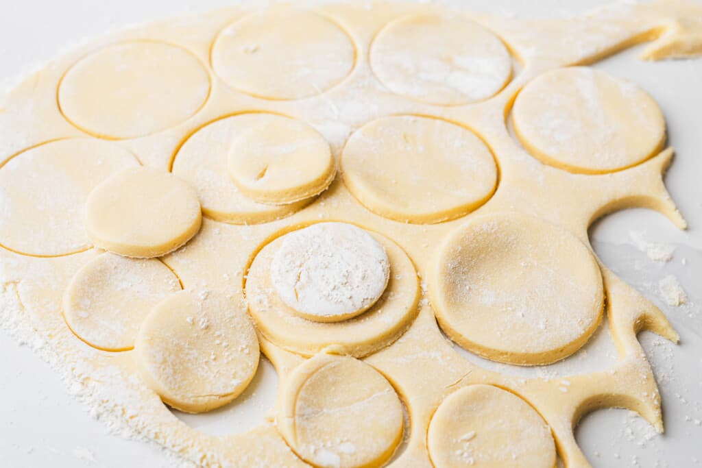 Circles of two different sizes have been cut into rolled out dough.