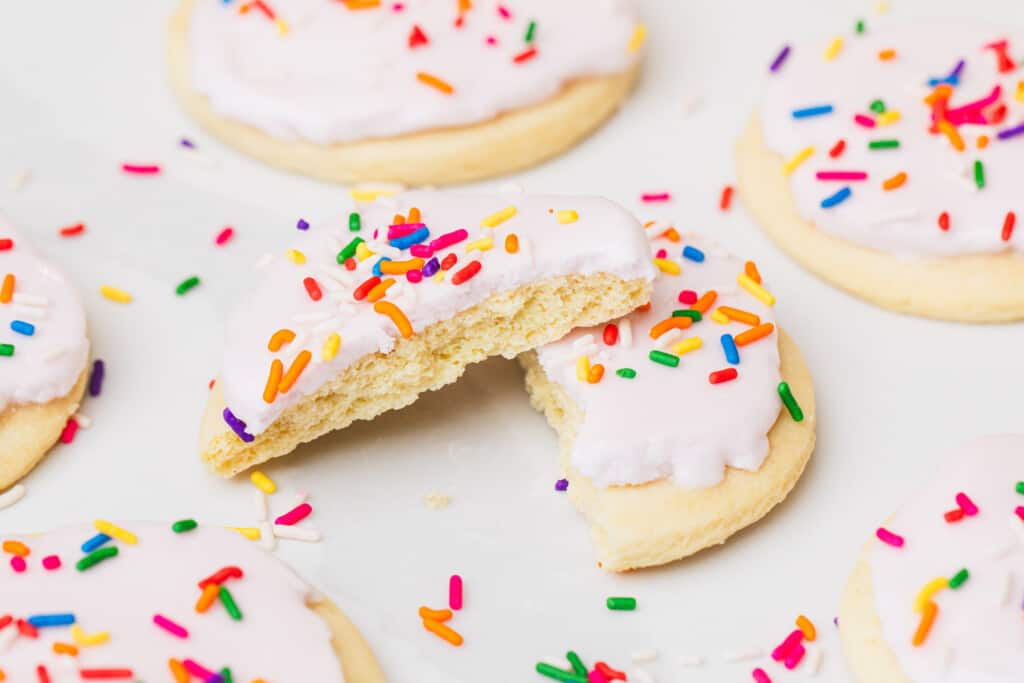 A sugar cookie is broken in half and lays showing the soft and tender inside.