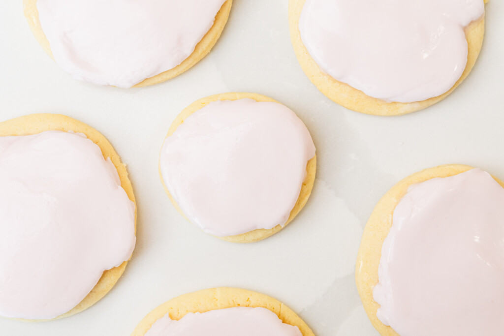Sugar cookies are covered in a layer of thick pink frosting.