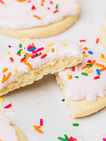 A sugar cookie is broken in half and lays showing the soft and tender inside.