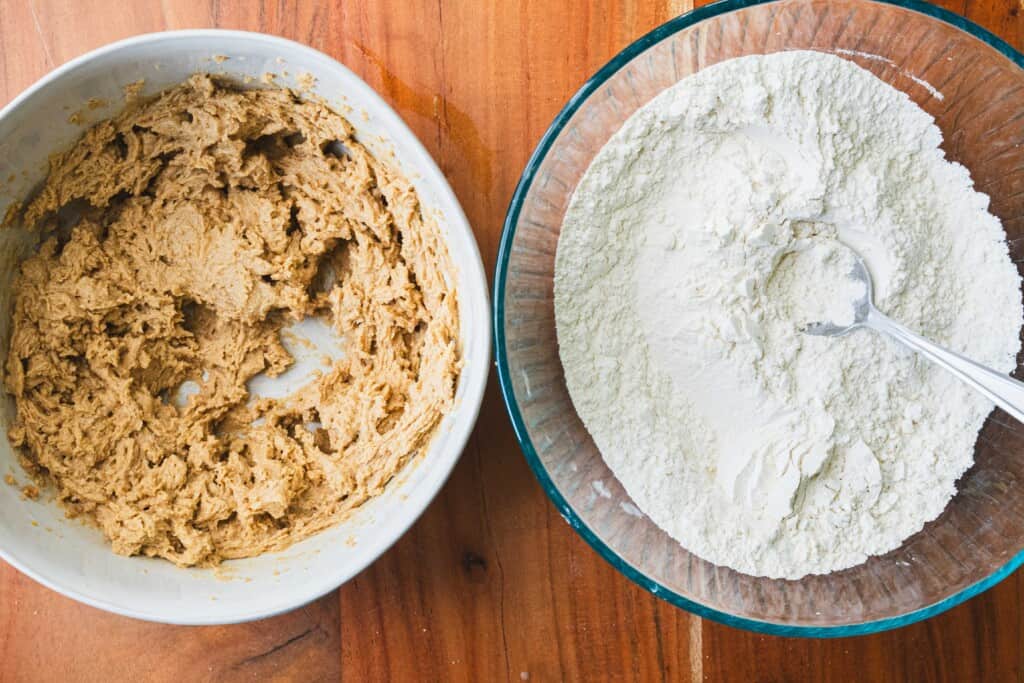 Two bowls, one with wet ingredients and the other with the dry ingredients for cookies sit side by side.