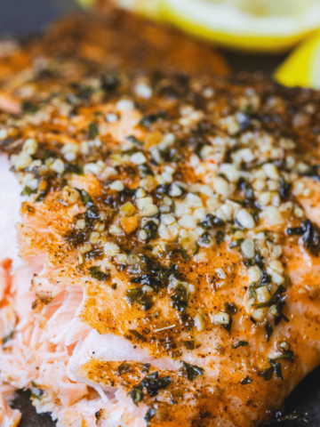 Lemon Garlic Salmon sits on a plate flaky and tender. Seasoned and golden brown it is ready to eat.