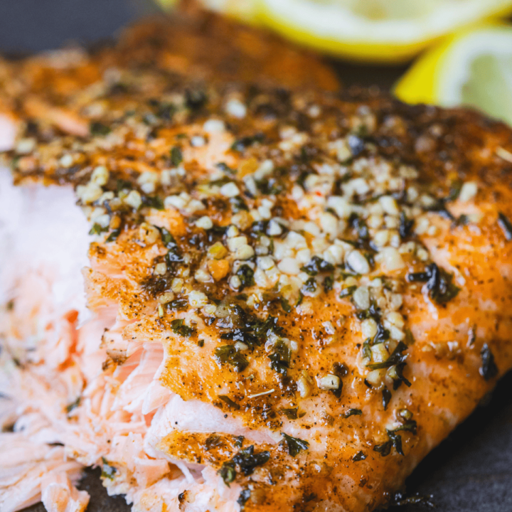 Lemon Garlic Salmon sits on a plate flaky and tender. Seasoned and golden brown it is ready to eat.