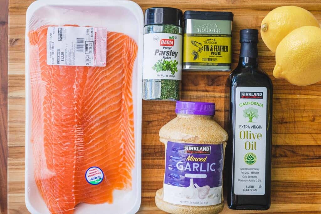 Ingredients for baked salmon sit on wooden cutting board.