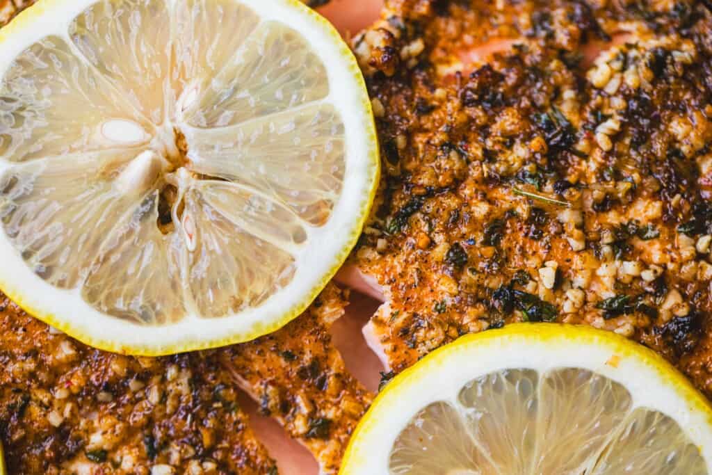 Seasoned salmon with lemon slices and garlic sits golden brown.