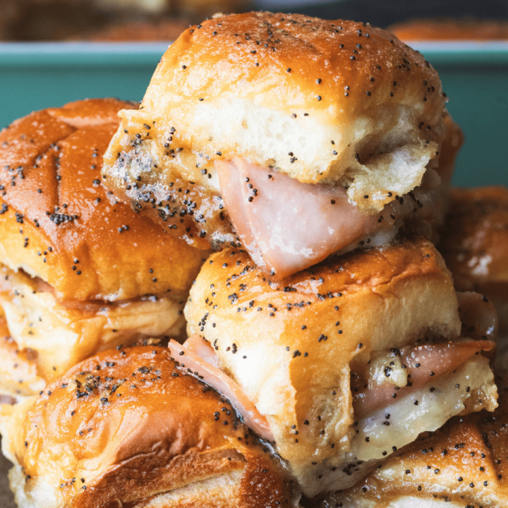 Ham and cheese sliders are stacked on a plate, toasty, melty and ready to enjoy.