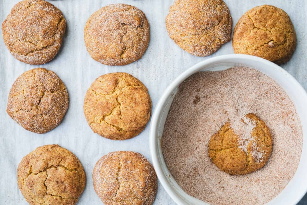 Freshly baked cookies sit next to a bowl of cinnamon sugar for double dipping.