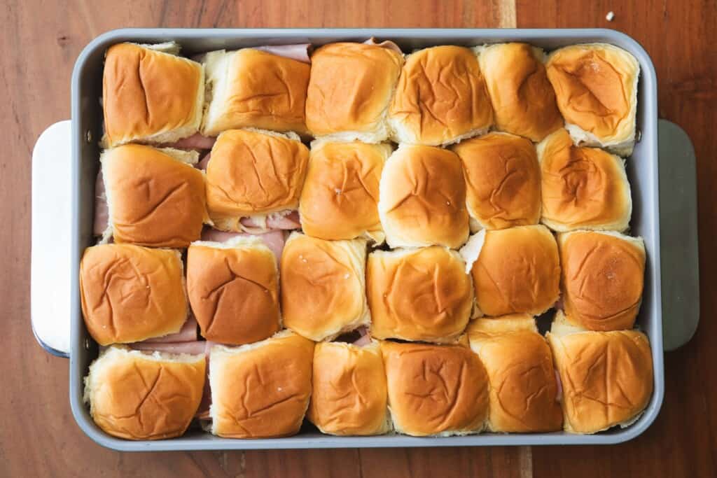 Assembled sandwiches are placed in a 9x13 casserole dish snuggly side by side.