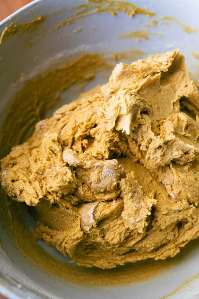 Dry and wet ingredients are combined in a bowl and mixed together to form cookie dough.