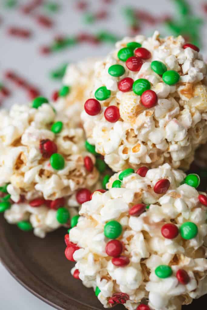 Formed and decorated popcorn balls are stacked on a dark plate.