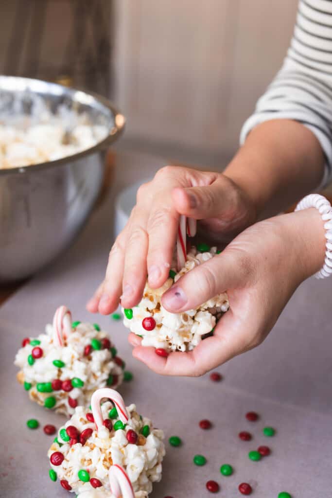 Hands insert a miniature candy cane into a formed treat to create an ornament hook.