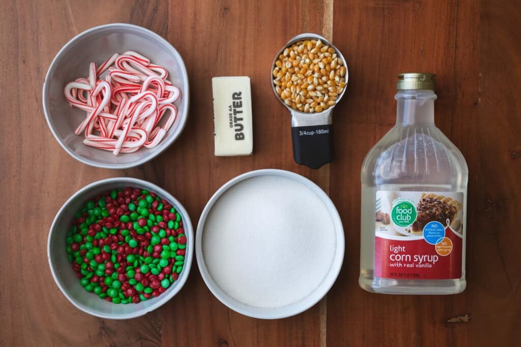 Ingredients for popcorn balls sit on a wooden counter in individual bowls.