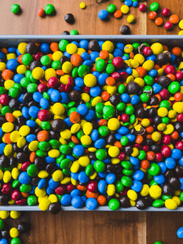 A baking dish is filled with colorful chocolate candies to make a delicious M&M's Casserole.