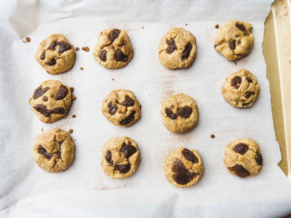 Twelve baked cookies sit on a parchment lined baking sheet.