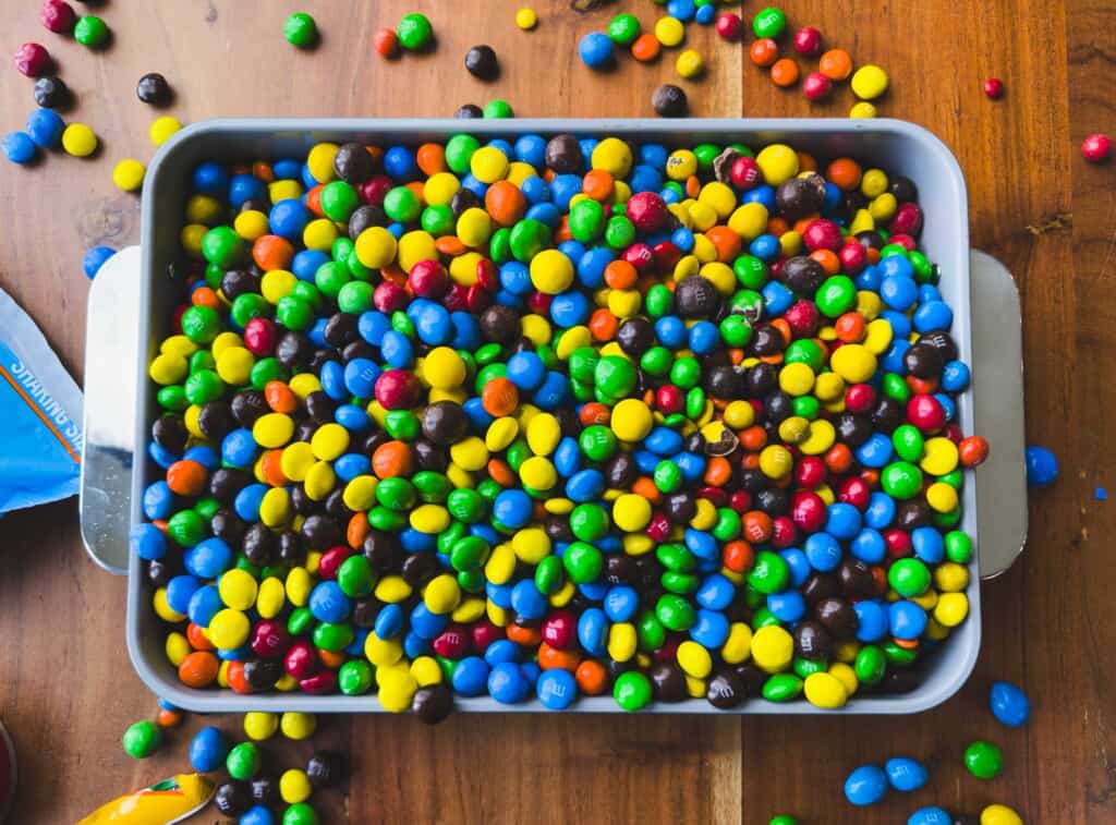 A baking dish is filled with colorful chocolate candies to make a delicious M&M's Casserole.
