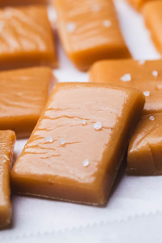 Rectangle salted cinnamon caramels lay on top of one another in a pile.