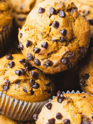 Pumpkin Muffins sit piled one on top of another in a basket ready for enjoying.