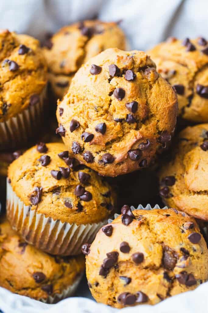 Basket of pumpkin chocolate chip muffins sit on a counter.